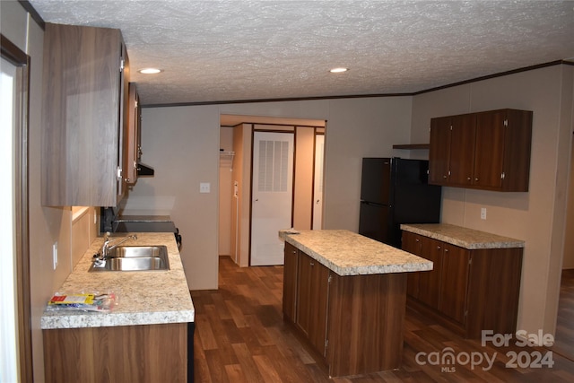 kitchen featuring sink, a textured ceiling, a center island, dark wood-type flooring, and black refrigerator