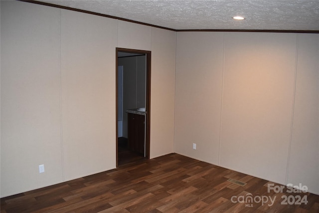 spare room with dark wood-type flooring, crown molding, and a textured ceiling