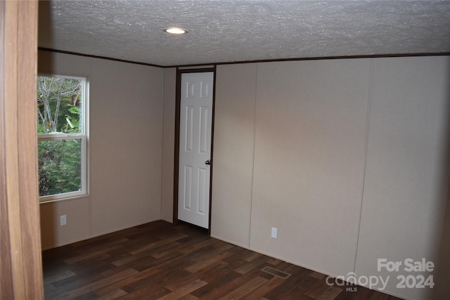 unfurnished bedroom with a textured ceiling and dark hardwood / wood-style flooring