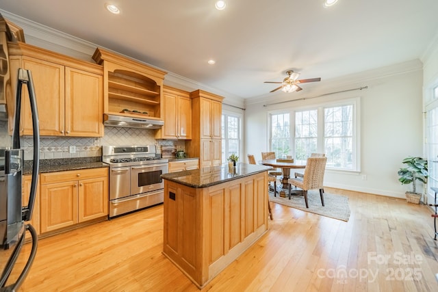 kitchen featuring a center island, dark stone countertops, ornamental molding, light hardwood / wood-style floors, and range with two ovens