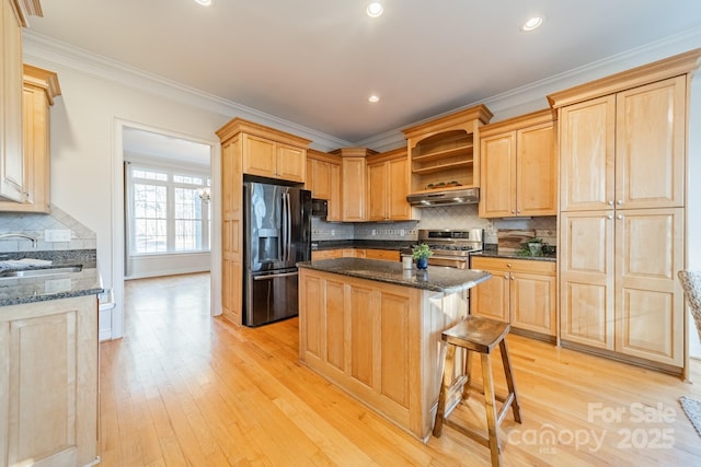 kitchen featuring sink, fridge with ice dispenser, a kitchen island, light brown cabinetry, and gas range