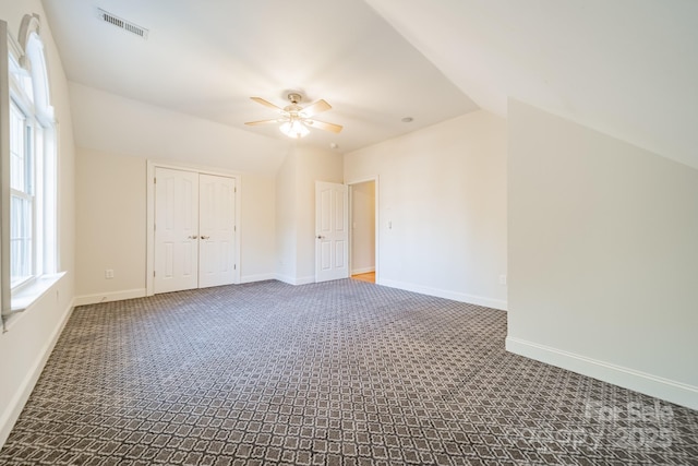 carpeted spare room featuring vaulted ceiling and ceiling fan