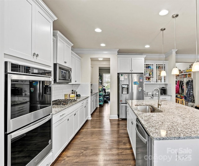 kitchen featuring sink, white cabinetry, pendant lighting, stainless steel appliances, and a kitchen island with sink