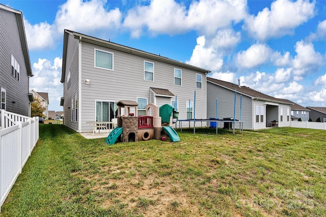 back of property featuring a playground, a patio area, a trampoline, and a lawn