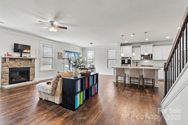 living room featuring baseboards, dark wood-type flooring, stairs, crown molding, and a fireplace