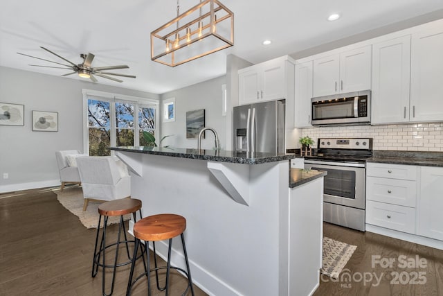 kitchen with white cabinetry, stainless steel appliances, and a kitchen island with sink