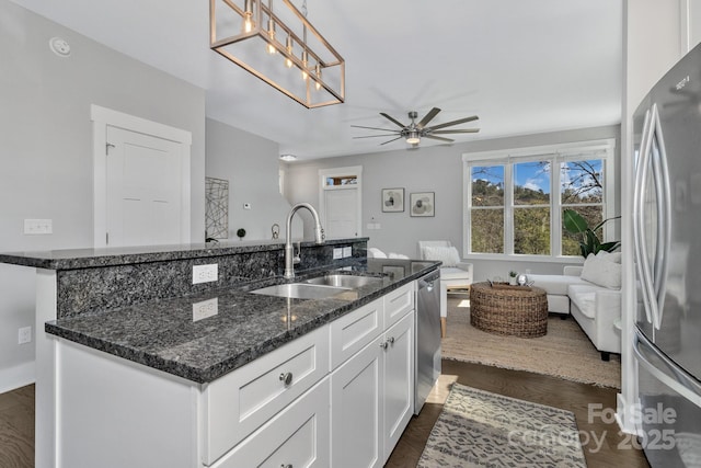 kitchen with sink, stainless steel appliances, dark stone countertops, pendant lighting, and white cabinets