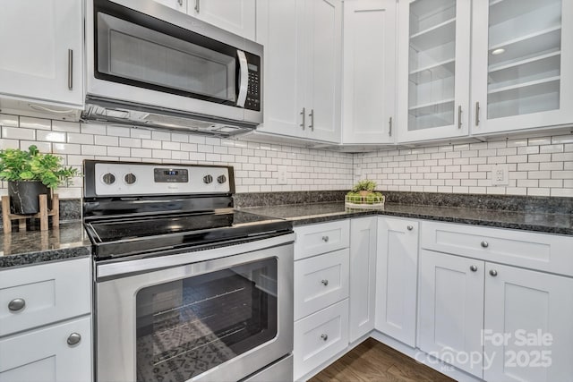 kitchen with dark stone countertops, dark hardwood / wood-style flooring, white cabinets, and stainless steel appliances