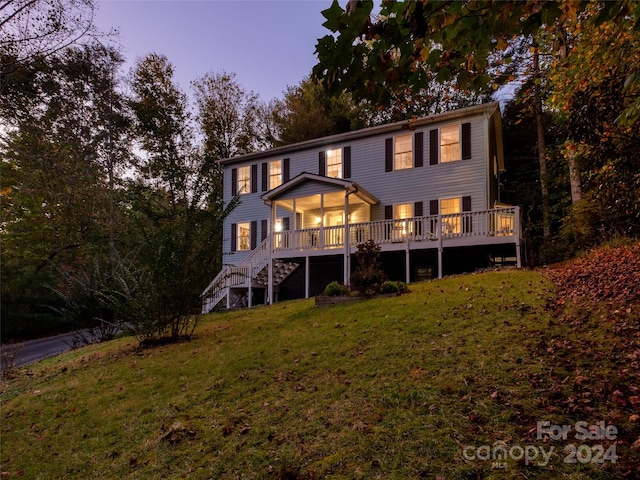 back house at dusk with a yard and a wooden deck