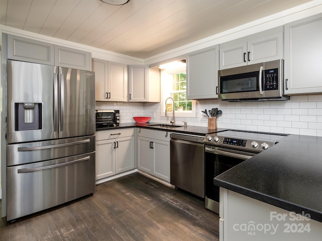 kitchen with dark hardwood / wood-style flooring, sink, stainless steel appliances, and tasteful backsplash