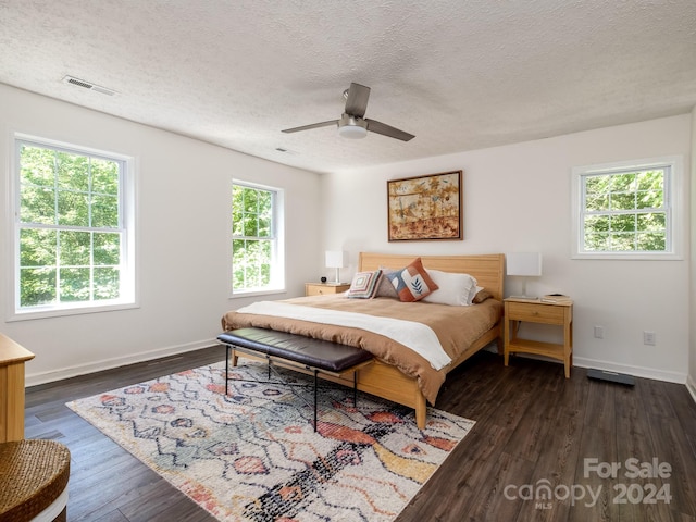 bedroom with a textured ceiling, ceiling fan, and dark hardwood / wood-style floors