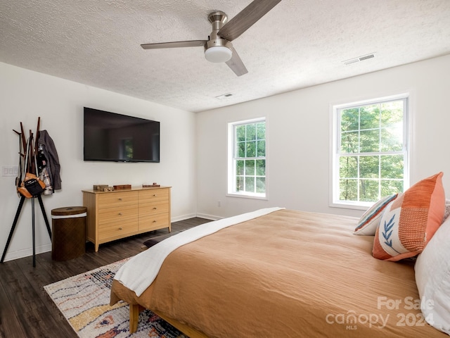 bedroom featuring multiple windows, a textured ceiling, dark hardwood / wood-style flooring, and ceiling fan