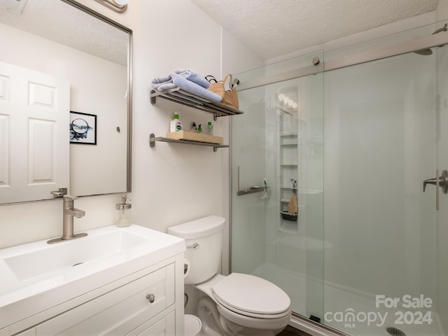 bathroom with walk in shower, vanity, a textured ceiling, and toilet