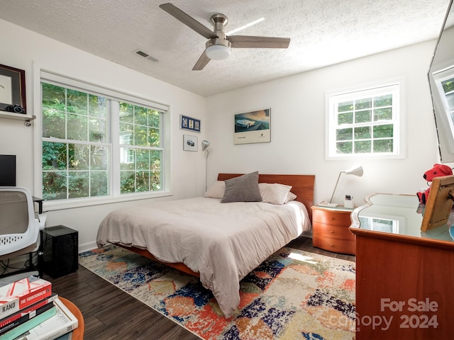 bedroom featuring ceiling fan, dark hardwood / wood-style flooring, and a textured ceiling