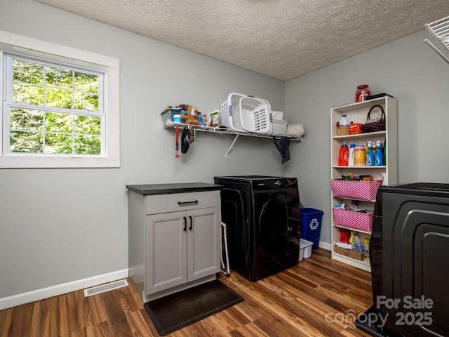 clothes washing area with a textured ceiling, cabinet space, dark wood finished floors, baseboards, and visible vents