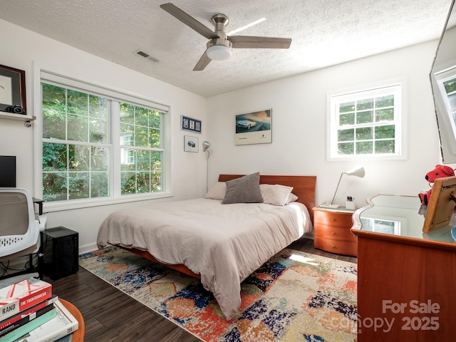 bedroom with multiple windows, wood finished floors, visible vents, and a textured ceiling