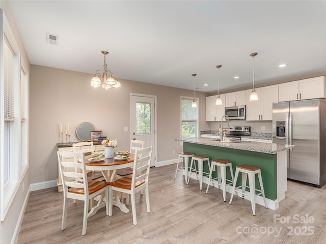 dining area with an inviting chandelier and light hardwood / wood-style flooring