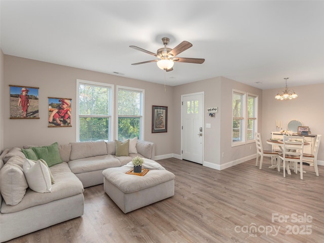 living room with hardwood / wood-style flooring and ceiling fan with notable chandelier