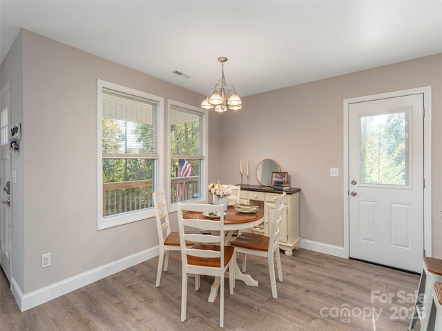 dining room with light hardwood / wood-style floors, an inviting chandelier, and plenty of natural light