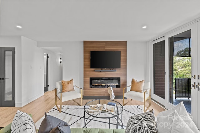 living room featuring light wood-type flooring and a large fireplace