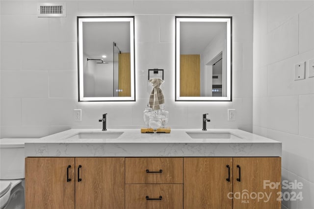 bathroom with vanity, tile walls, and toilet