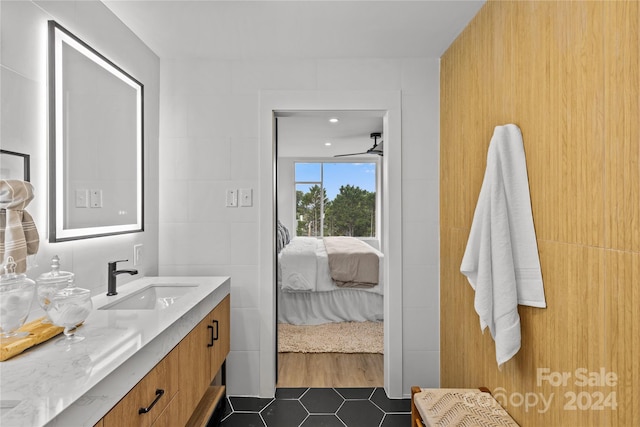 bathroom with tile walls, tile patterned flooring, ceiling fan, and vanity