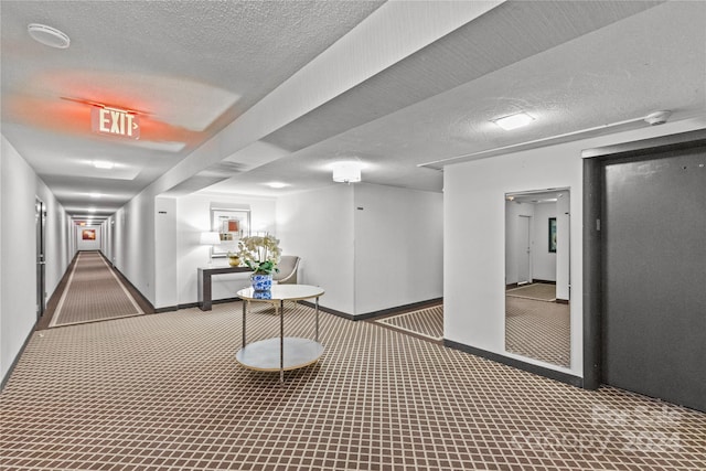 corridor with a textured ceiling and carpet