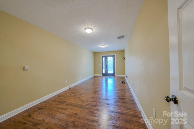 empty room with dark hardwood / wood-style floors and a textured ceiling