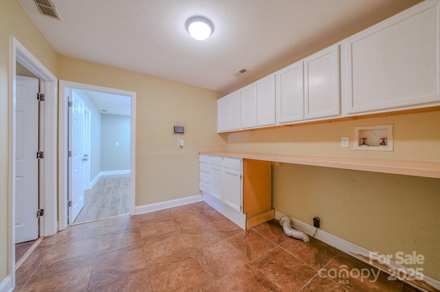 washroom with cabinets, washer hookup, and a textured ceiling