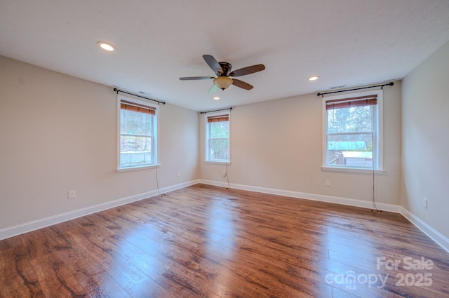 spare room with ceiling fan, wood-type flooring, and a wealth of natural light