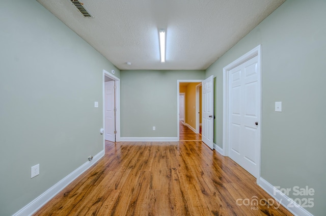 unfurnished room featuring a textured ceiling and light wood-type flooring