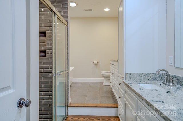 bathroom featuring tile patterned floors, vanity, toilet, and a shower with door