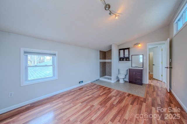 unfurnished living room featuring wood-type flooring, sink, vaulted ceiling, and a textured ceiling