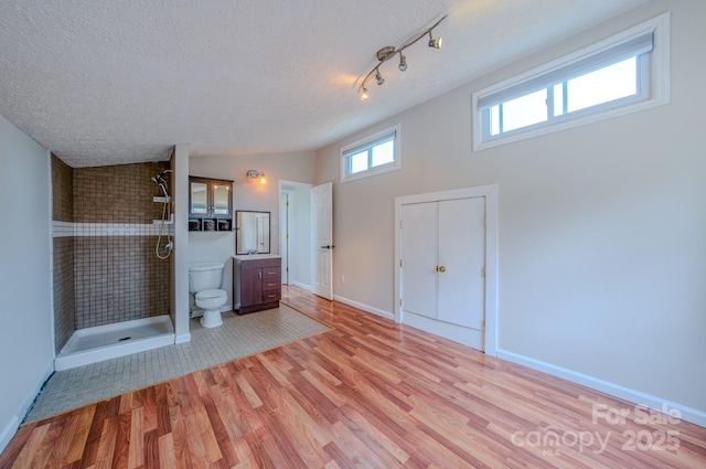 bathroom featuring hardwood / wood-style flooring, vanity, walk in shower, toilet, and a textured ceiling