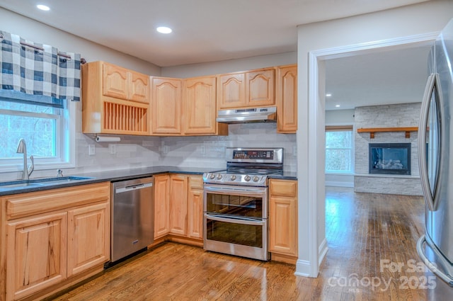 kitchen featuring light brown cabinetry, sink, light hardwood / wood-style flooring, and appliances with stainless steel finishes