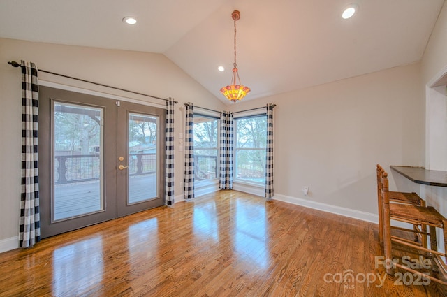 unfurnished dining area featuring vaulted ceiling, hardwood / wood-style floors, and french doors