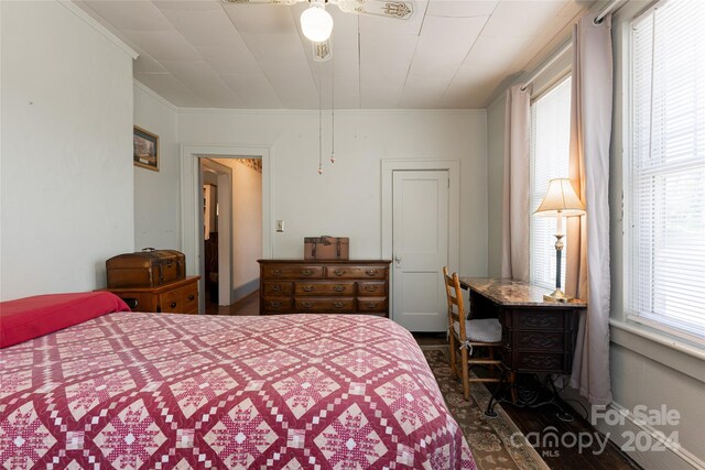 bedroom with dark hardwood / wood-style floors, crown molding, and ceiling fan