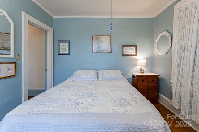 bedroom featuring baseboards, crown molding, and dark wood-type flooring