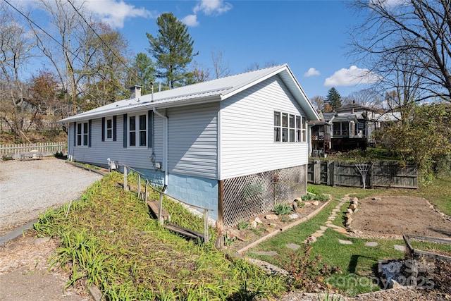view of side of home with metal roof and fence
