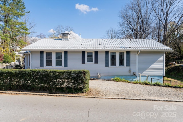 view of front of property featuring metal roof, a chimney, and fence