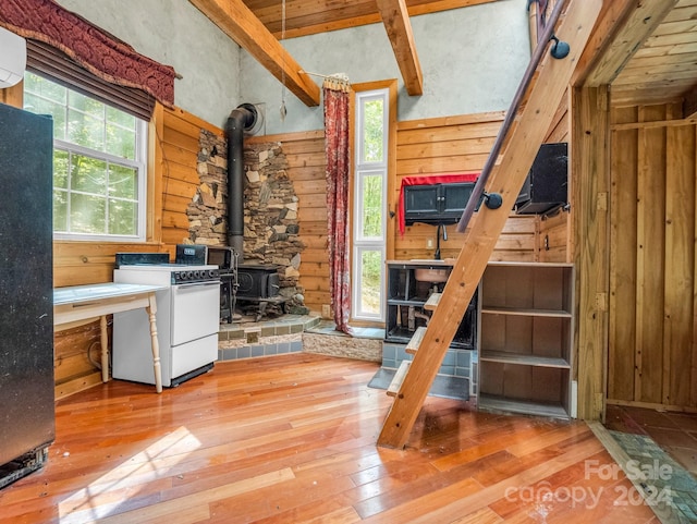 interior space featuring wood-type flooring, wooden walls, and a wood stove