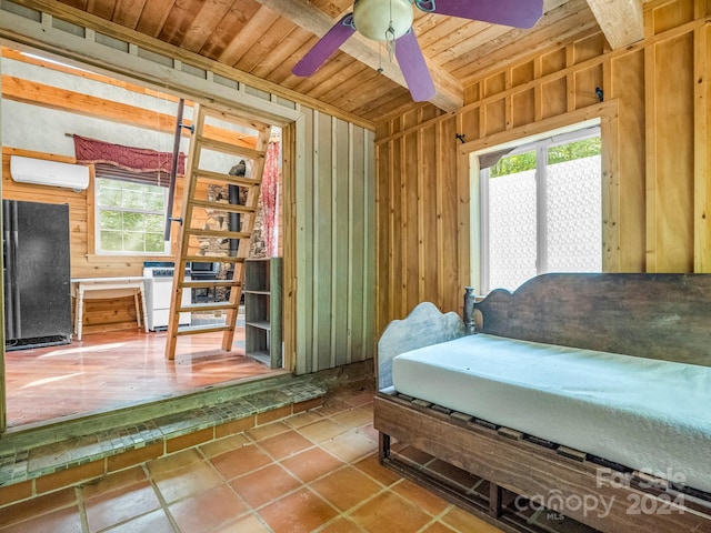 tiled bedroom featuring ceiling fan, black fridge, wood walls, a wall mounted AC, and wooden ceiling