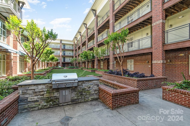 view of patio / terrace featuring a grill, a balcony, and exterior kitchen