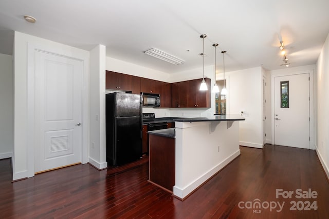 kitchen featuring dark brown cabinetry, pendant lighting, black appliances, a breakfast bar area, and dark hardwood / wood-style flooring