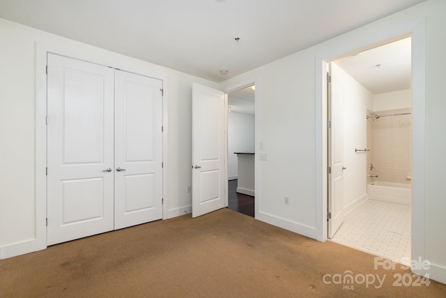 unfurnished bedroom with a closet, ensuite bath, and carpet