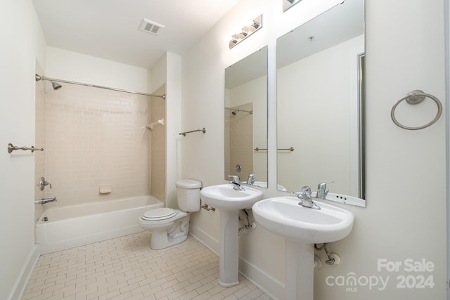 bathroom with tile patterned flooring, tiled shower / bath, and toilet