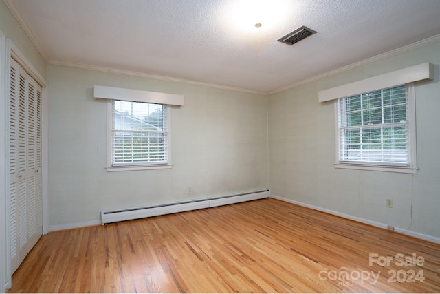 unfurnished bedroom with a baseboard radiator, light wood-type flooring, crown molding, and a closet