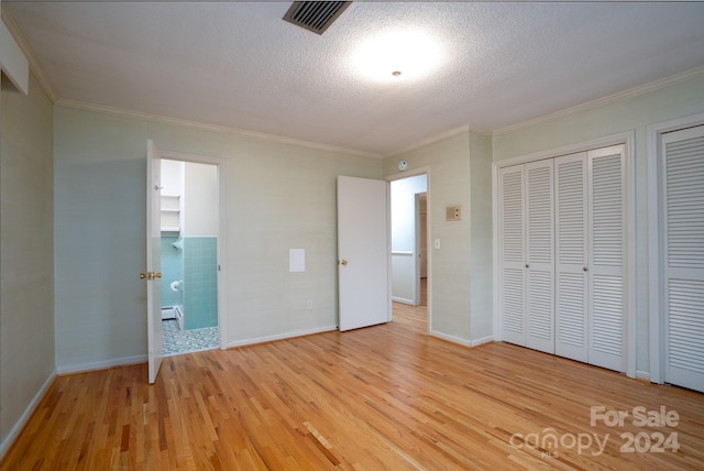 unfurnished bedroom with a textured ceiling, ensuite bathroom, crown molding, and light hardwood / wood-style flooring