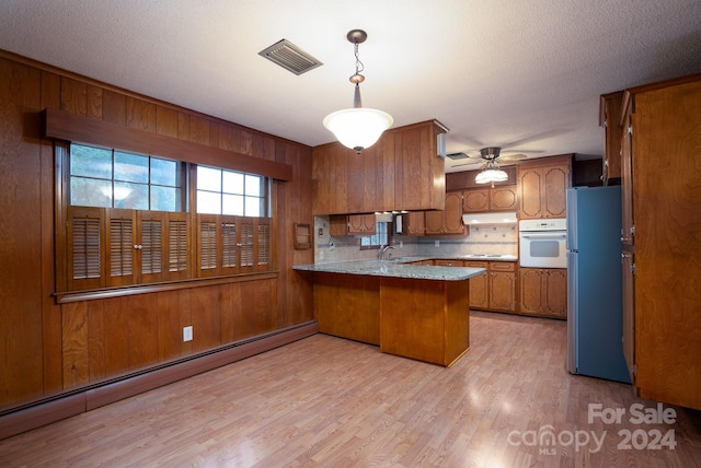 kitchen with light wood-type flooring, stainless steel refrigerator, a baseboard heating unit, kitchen peninsula, and white oven