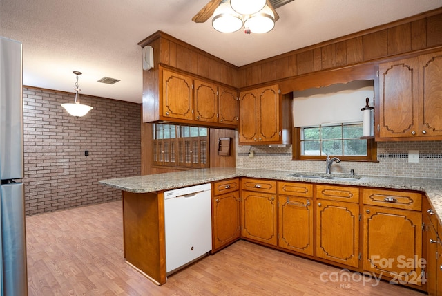 kitchen featuring light wood-type flooring, brick wall, decorative light fixtures, dishwasher, and kitchen peninsula